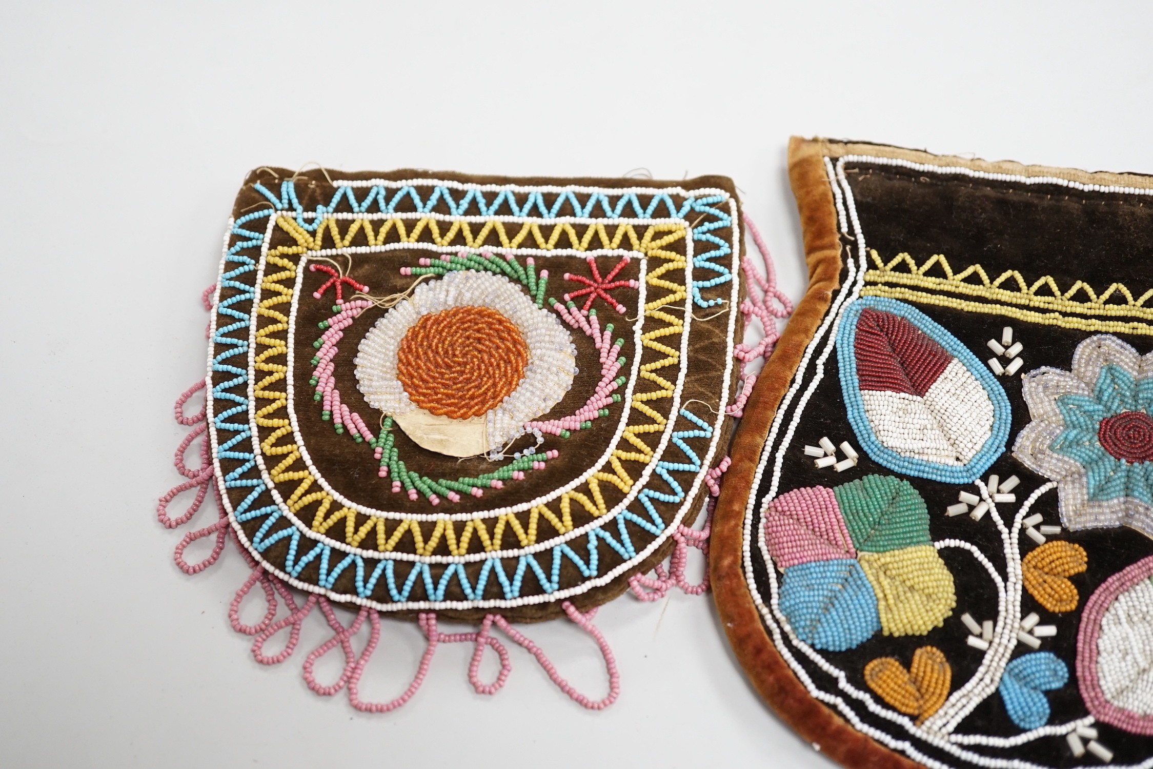 A pair of mid to late 19th century Mikmaq, North American Indian, moccasins, worked in floral beadwork on vamp, with velvet cuffs and red silk ties, together with two Wabanaki floral bead-worked velvet bags